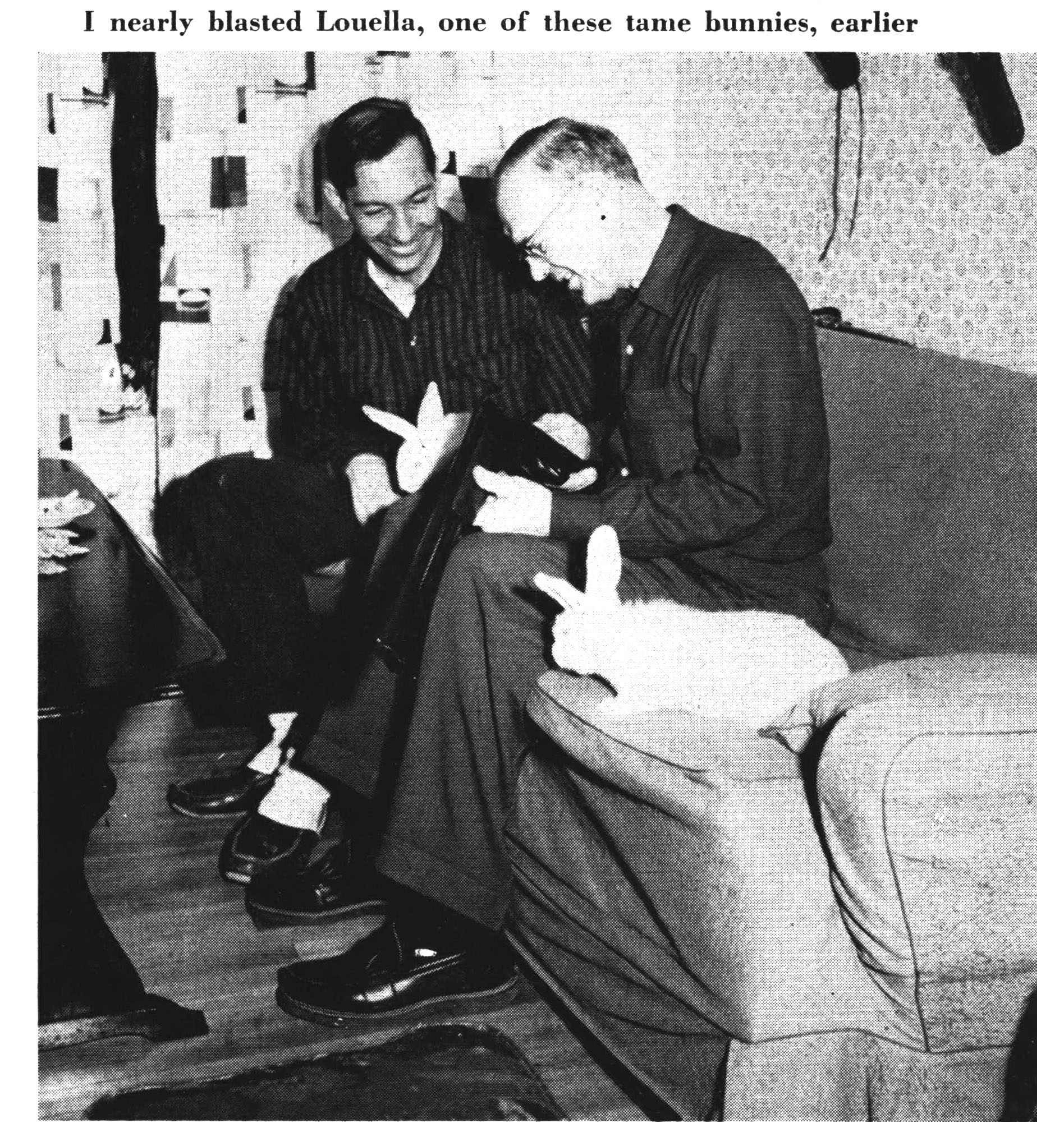 Two men sit on a couch next to a domestic rabbit in an old black and white photo