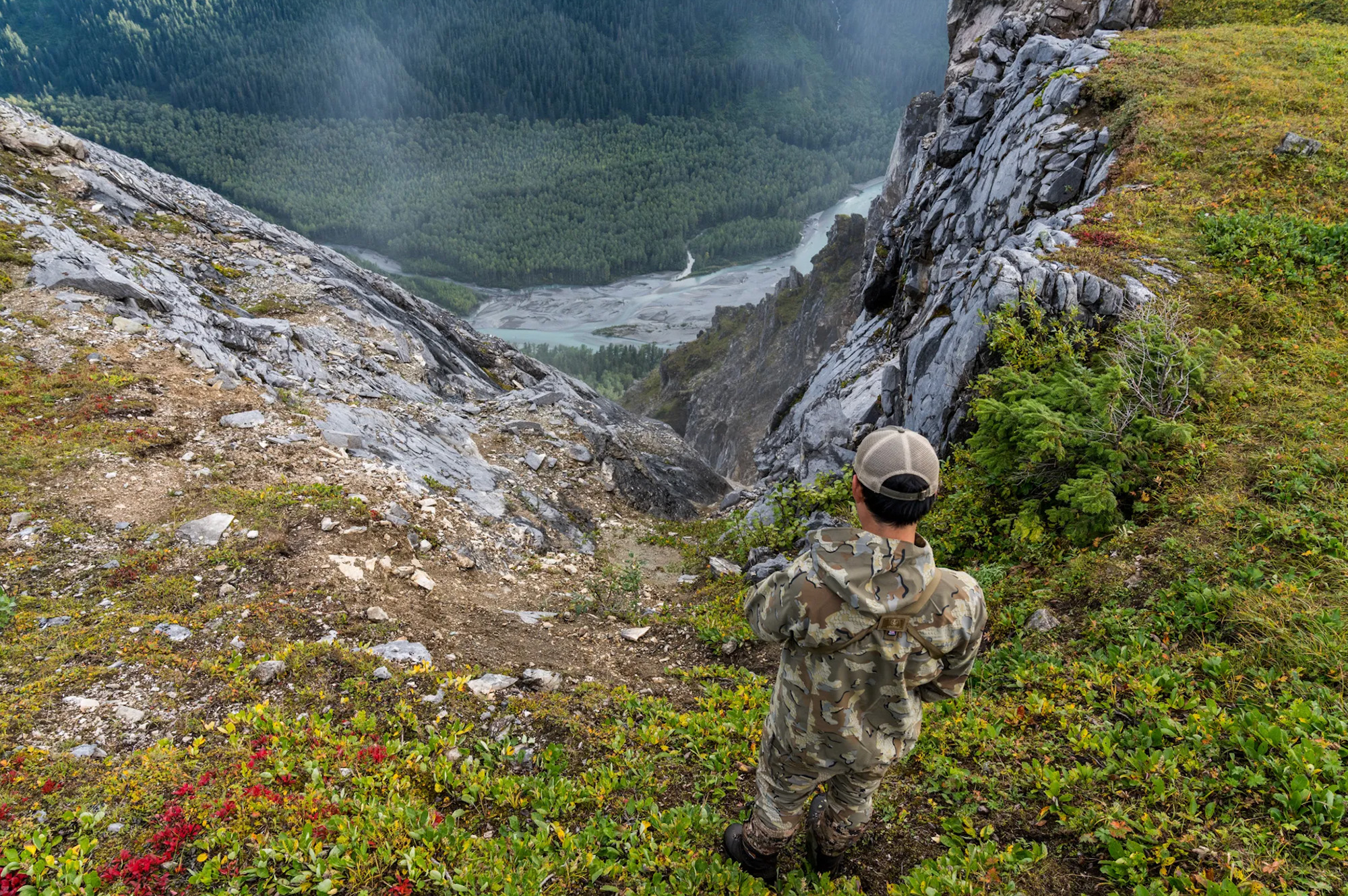 A hunter wearing kuiu looks down into a ravine