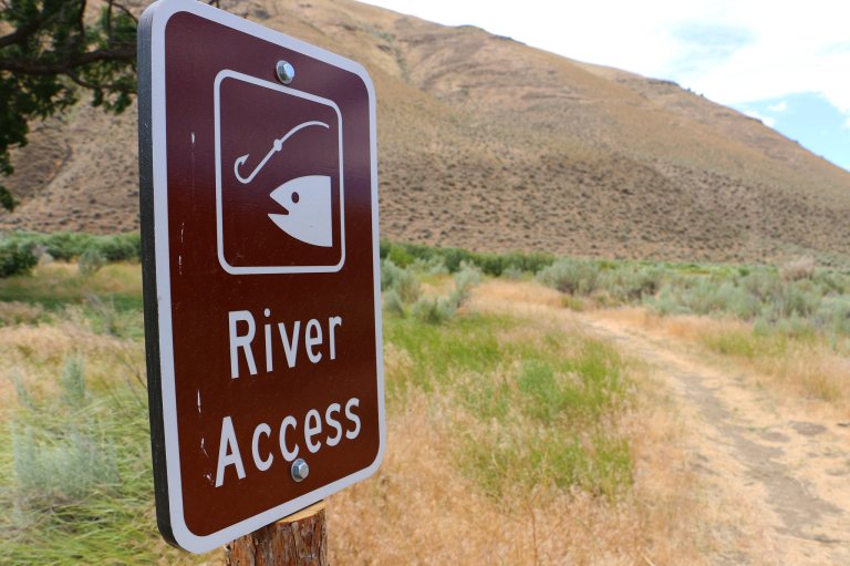 A brown river access sign with a fish on it.