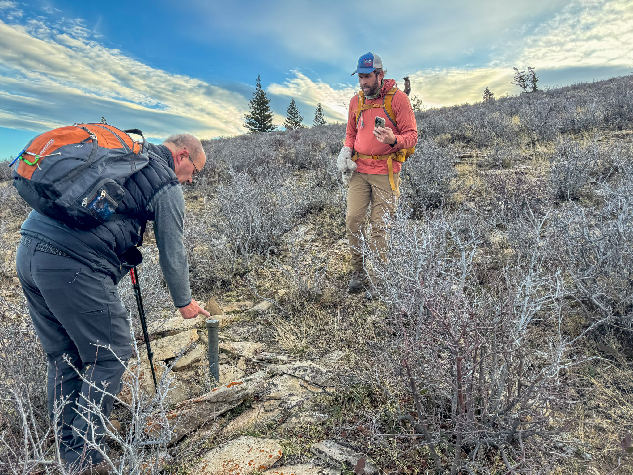 Two hikers examine a corner post