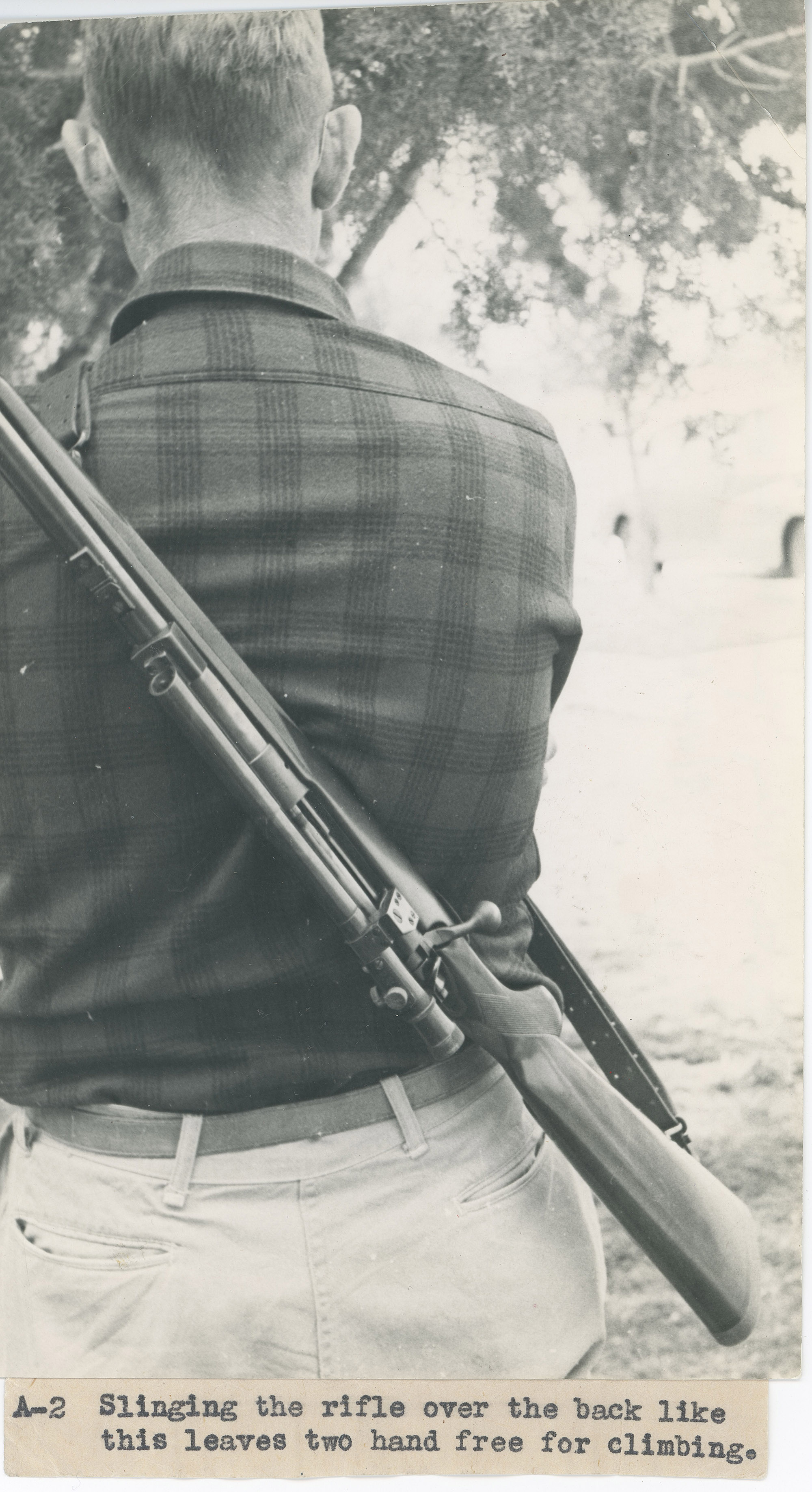 A black and white photo of a rifle slung over JOC's back.