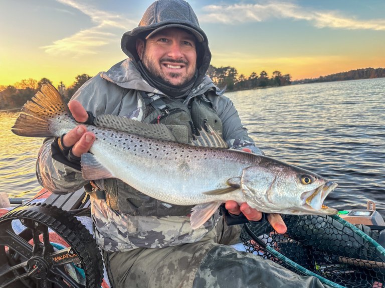 A kayak fisherman holds up a nice sea trout