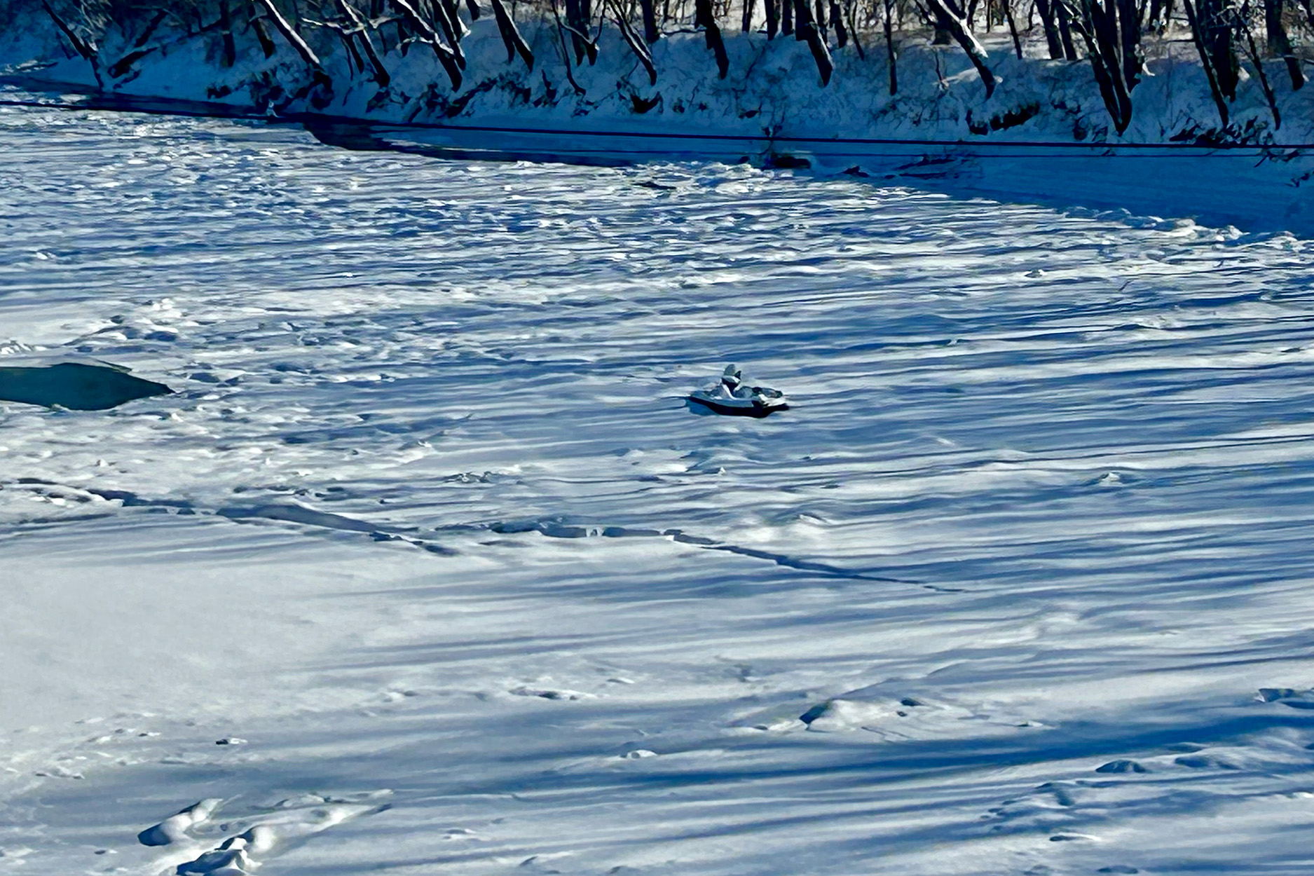 A jon boat stuck in a frozen river.