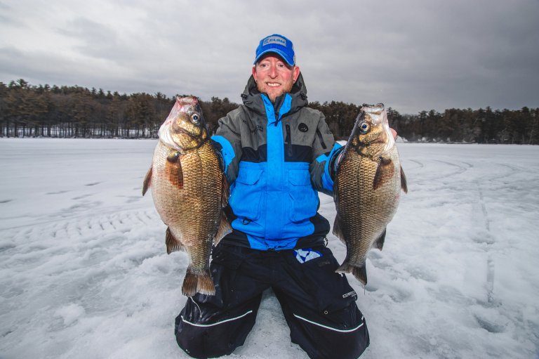 A photo of an ice fisherman holding up two white perch.