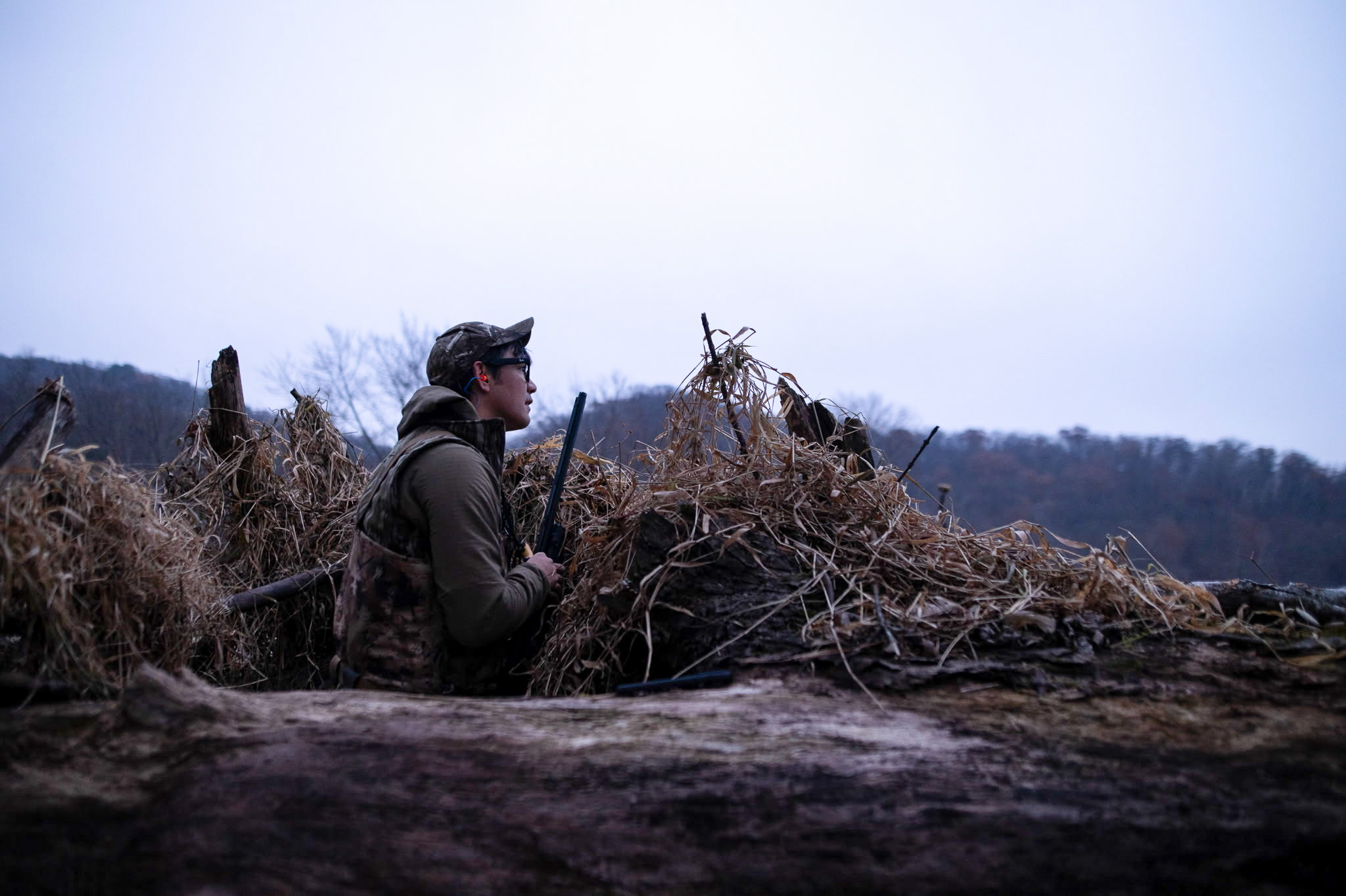 A hunter hides behind a brush pile.