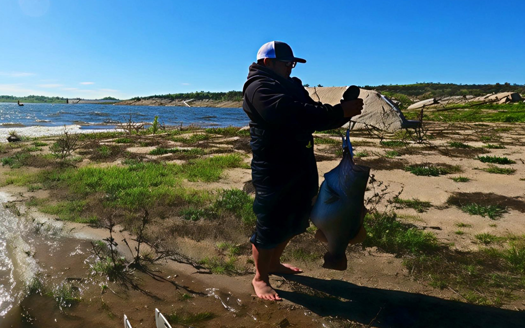 An angler weighs a huge largemouth bass on land.