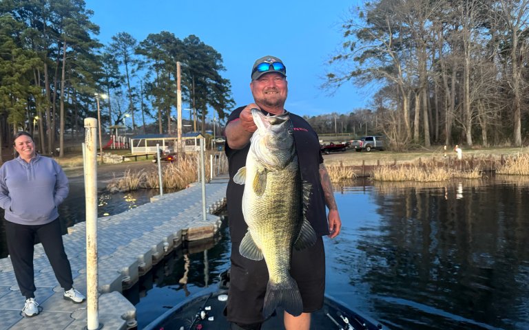 A fisherman holds up a big bass.