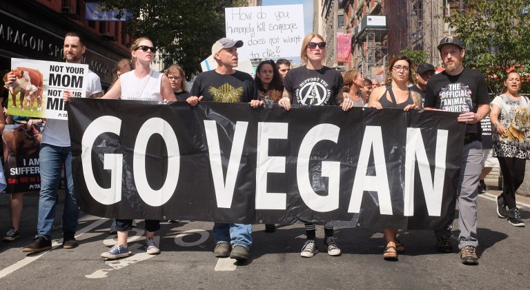 Animal rights activists hold a sign that reads "go vegan." Activists in Oregon are pushing for a ballot initiative to ban all hunting, fishing, livestock production.