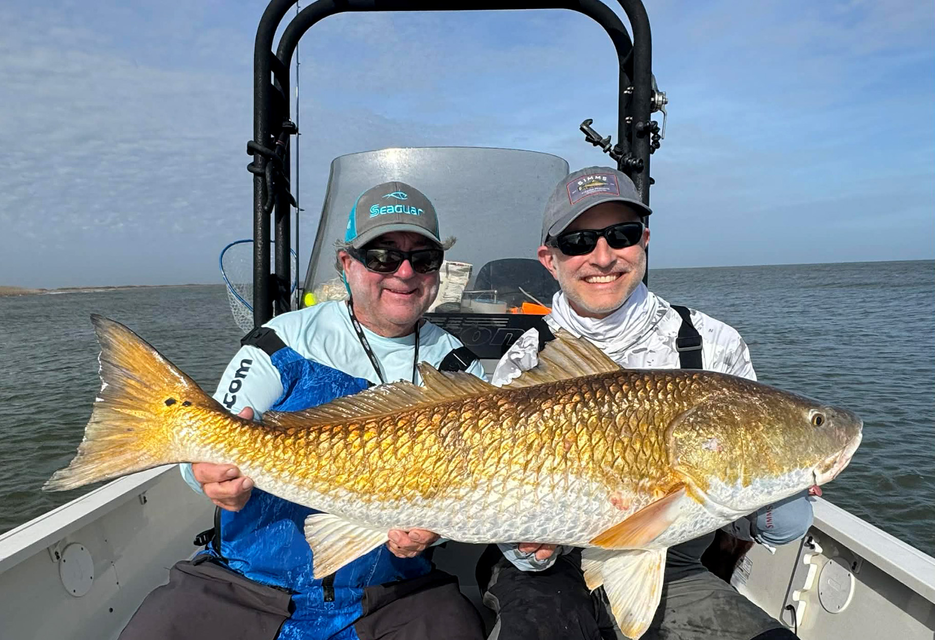 A Louisiana guide and a fisherman hold up a huge Louisiana redfish.