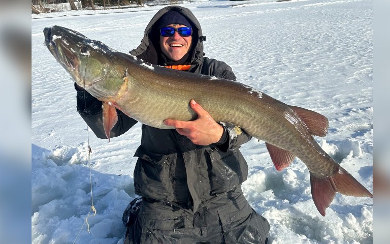 An angler with a record-sized muskie caught through the ice.