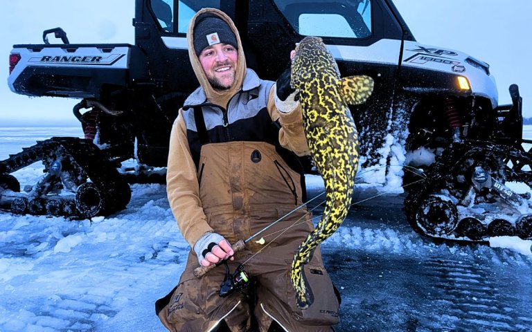 An angler holds up a burbot he landed while ice fishing.