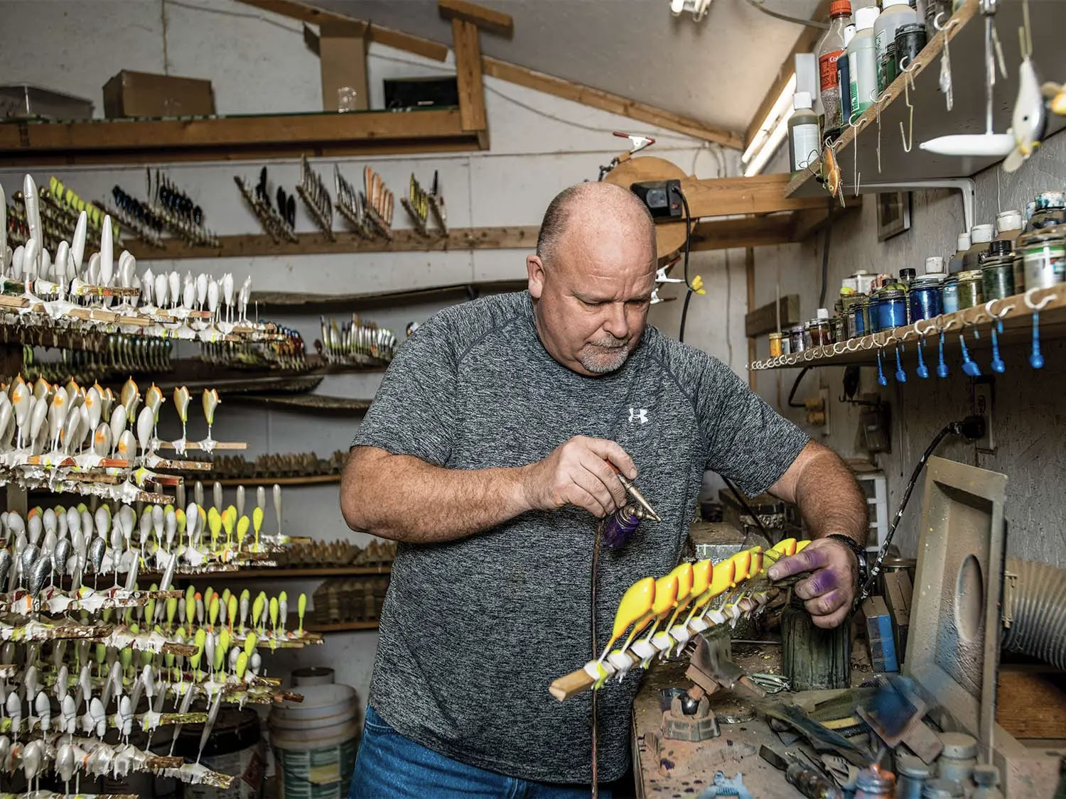 Hunt airbrushes a batch of balsa baits in his studio.