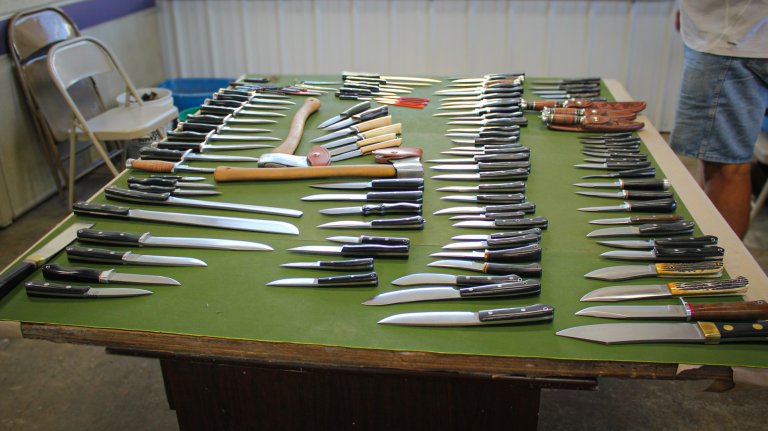 A table with green felt with Bark River Knives laid out on top of it.