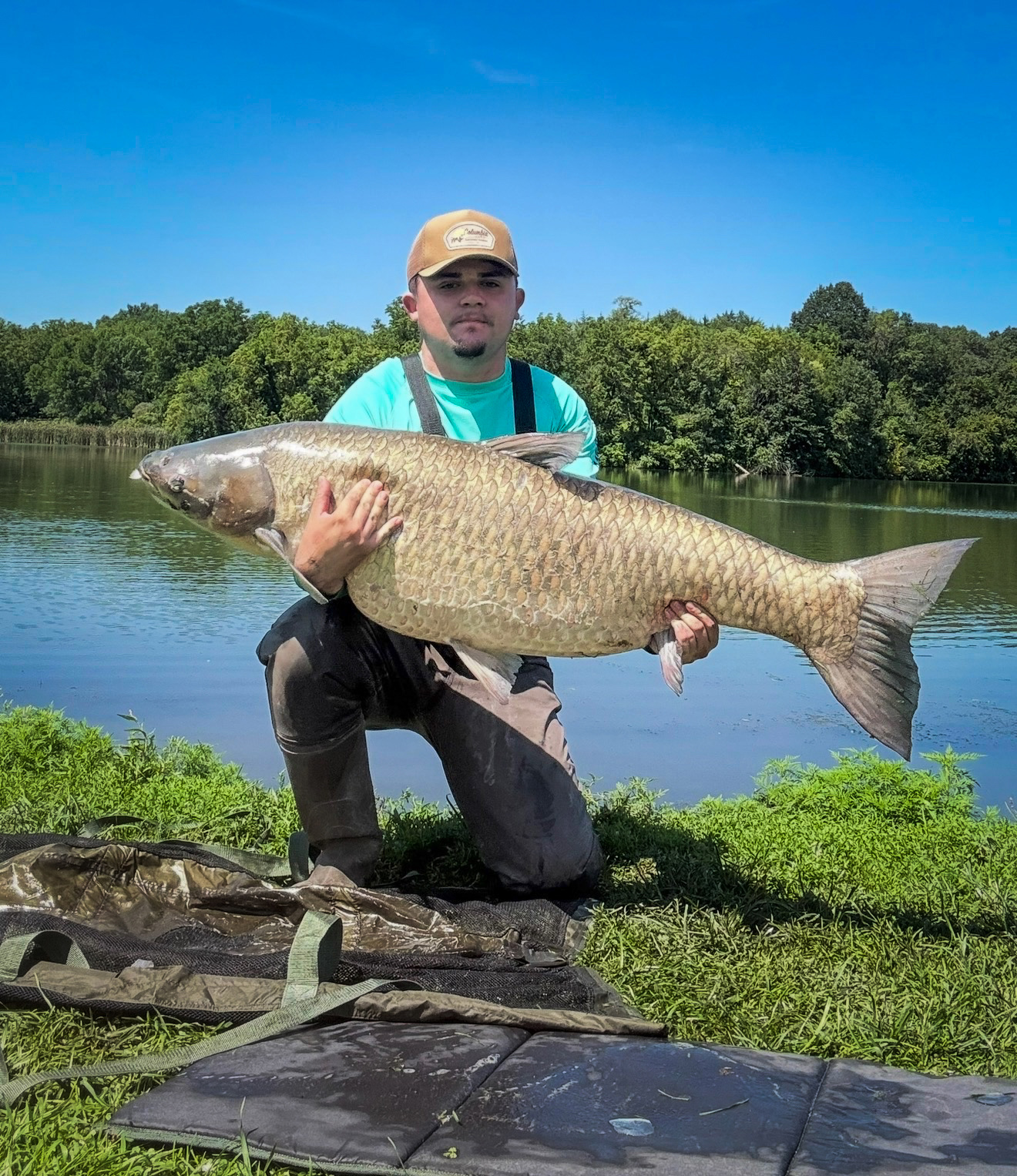 a fisherman holds up a world-record carp.