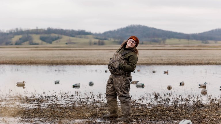 A duck hunter smiles in the marsh.