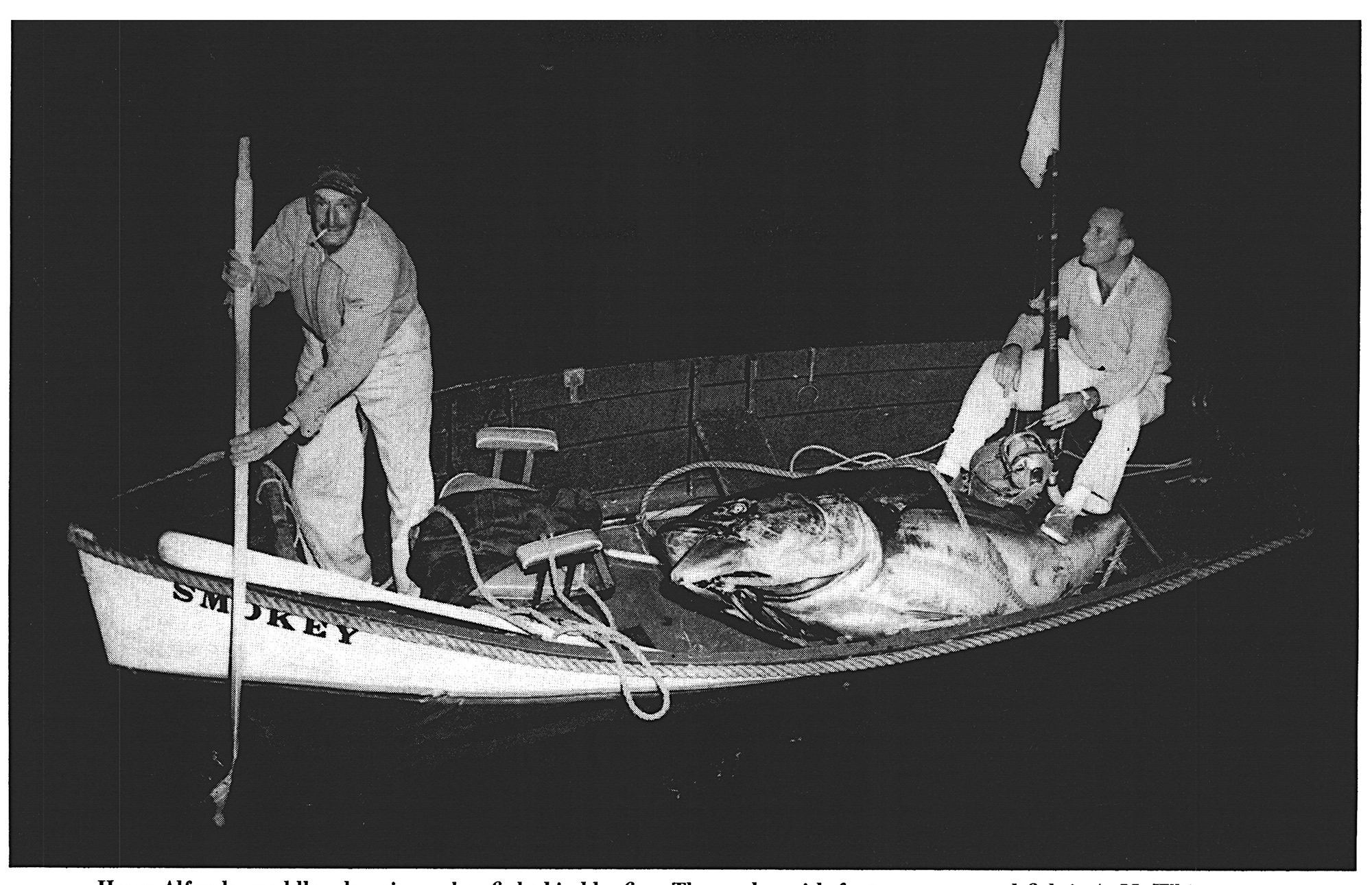 a black and white photo of two fishermen in a skiff with a big tuna.