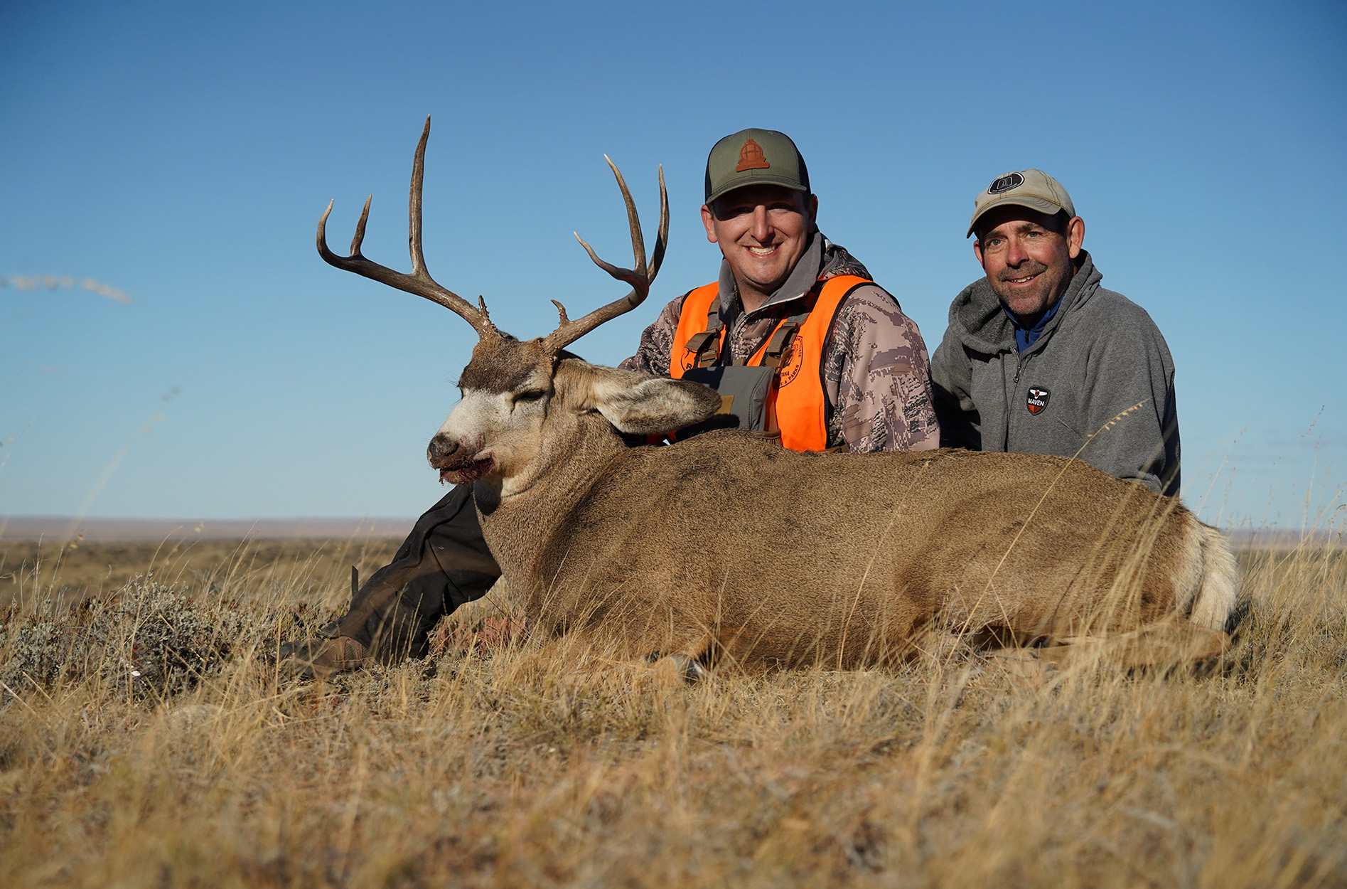 Two hunters sit with a big prairie buck tagged in Montana.