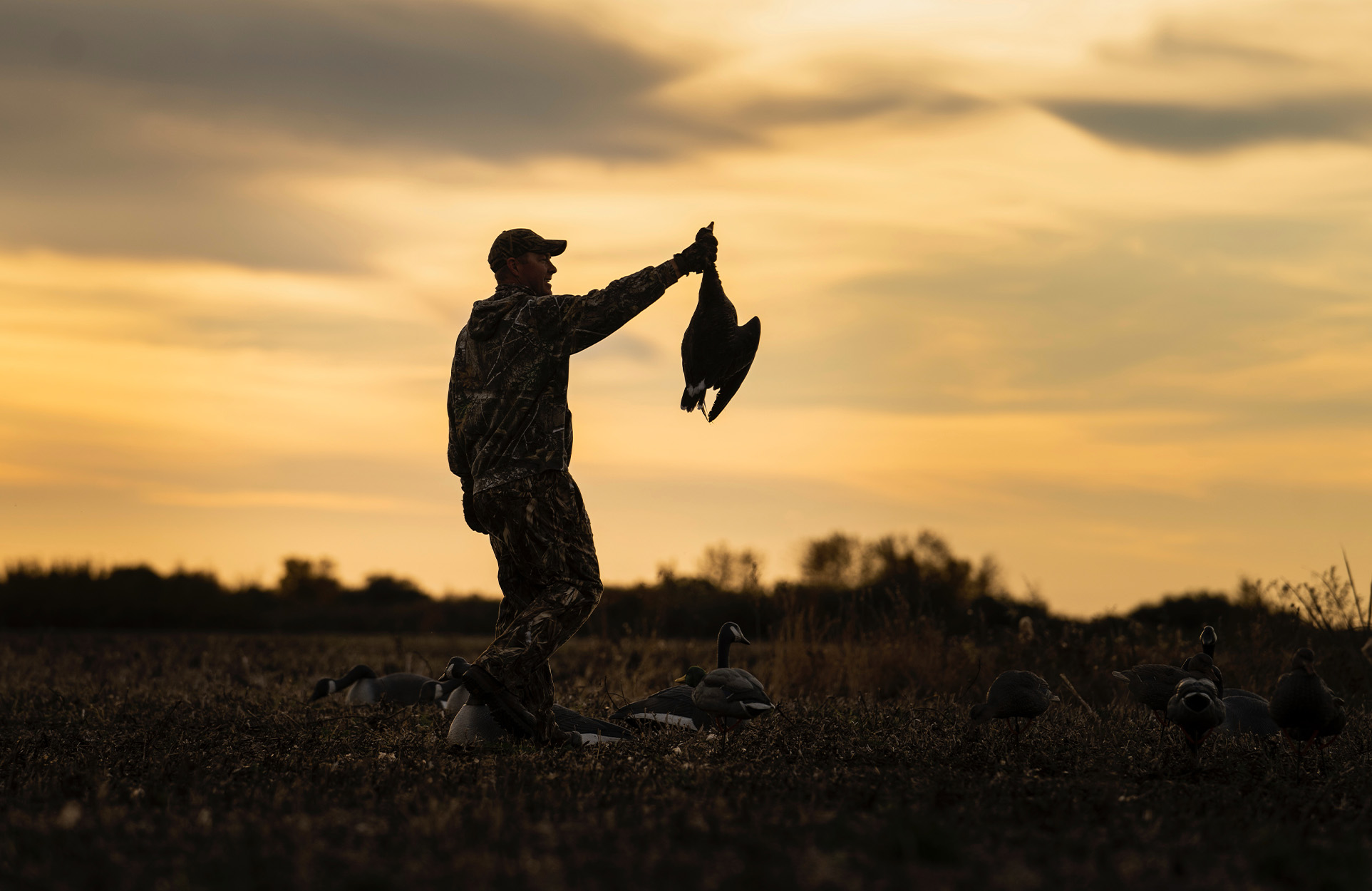 A waterfowl hunter in Canada holds up a goose.