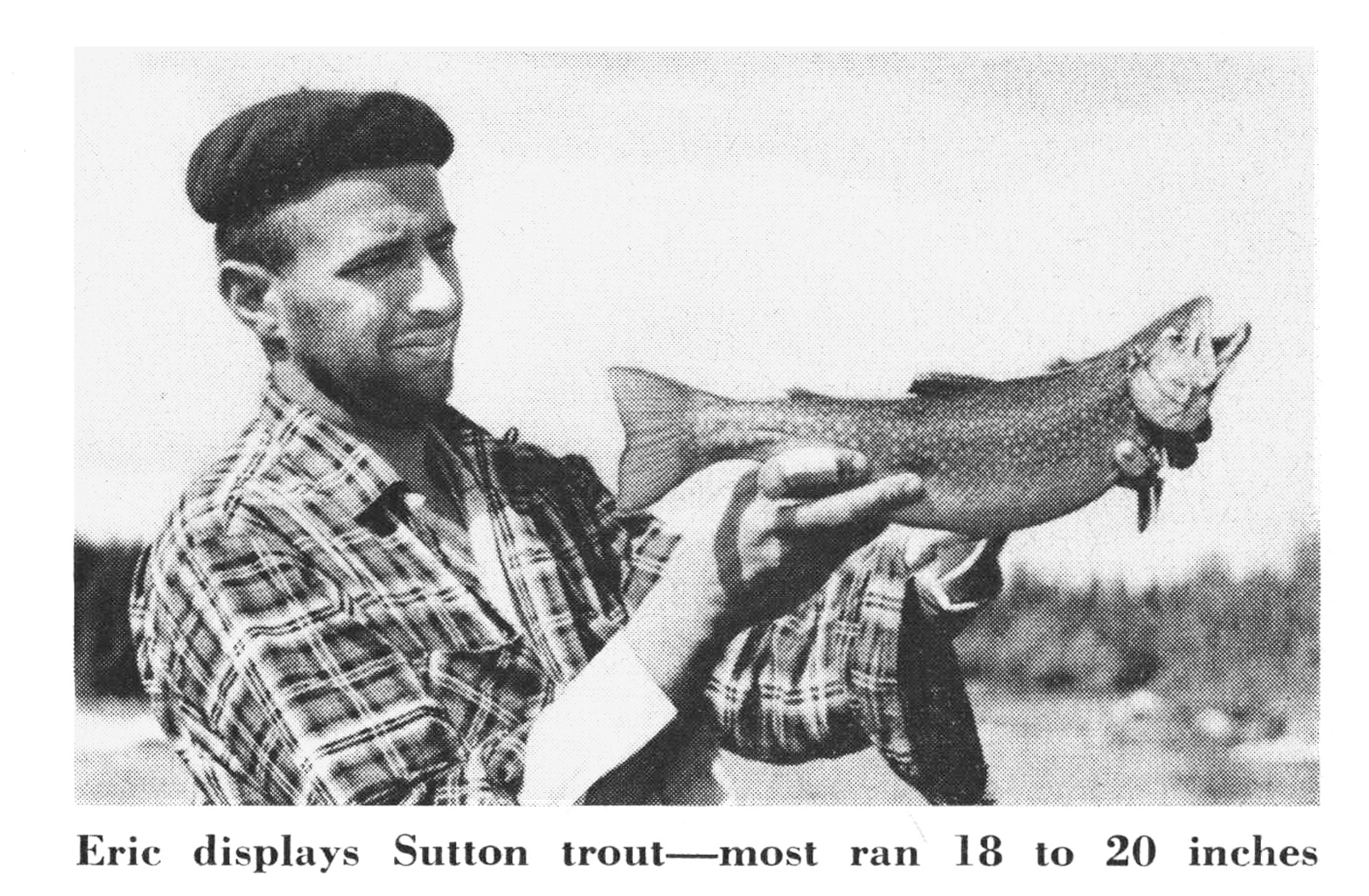 A black and white photograph of a fisherman holding up a trout.