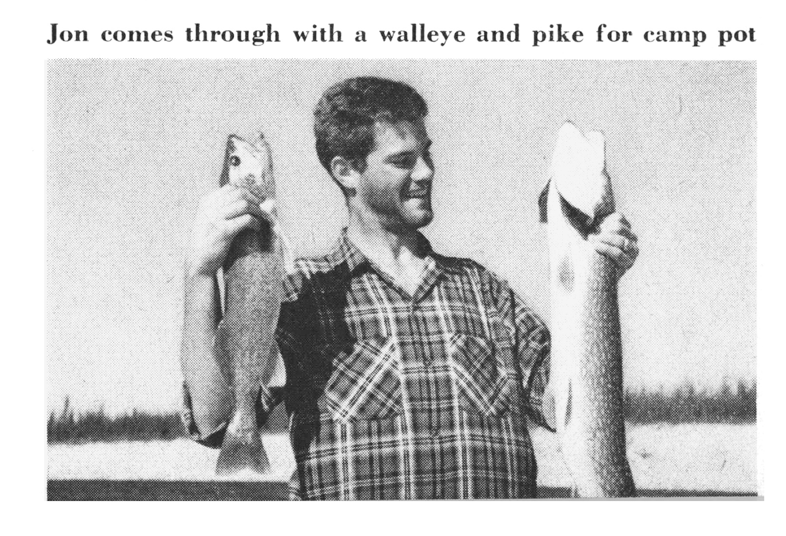 A black and white photograph of a fisherman holding up a pike and walleye