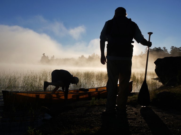 A man hops in a canoe in the BWCA