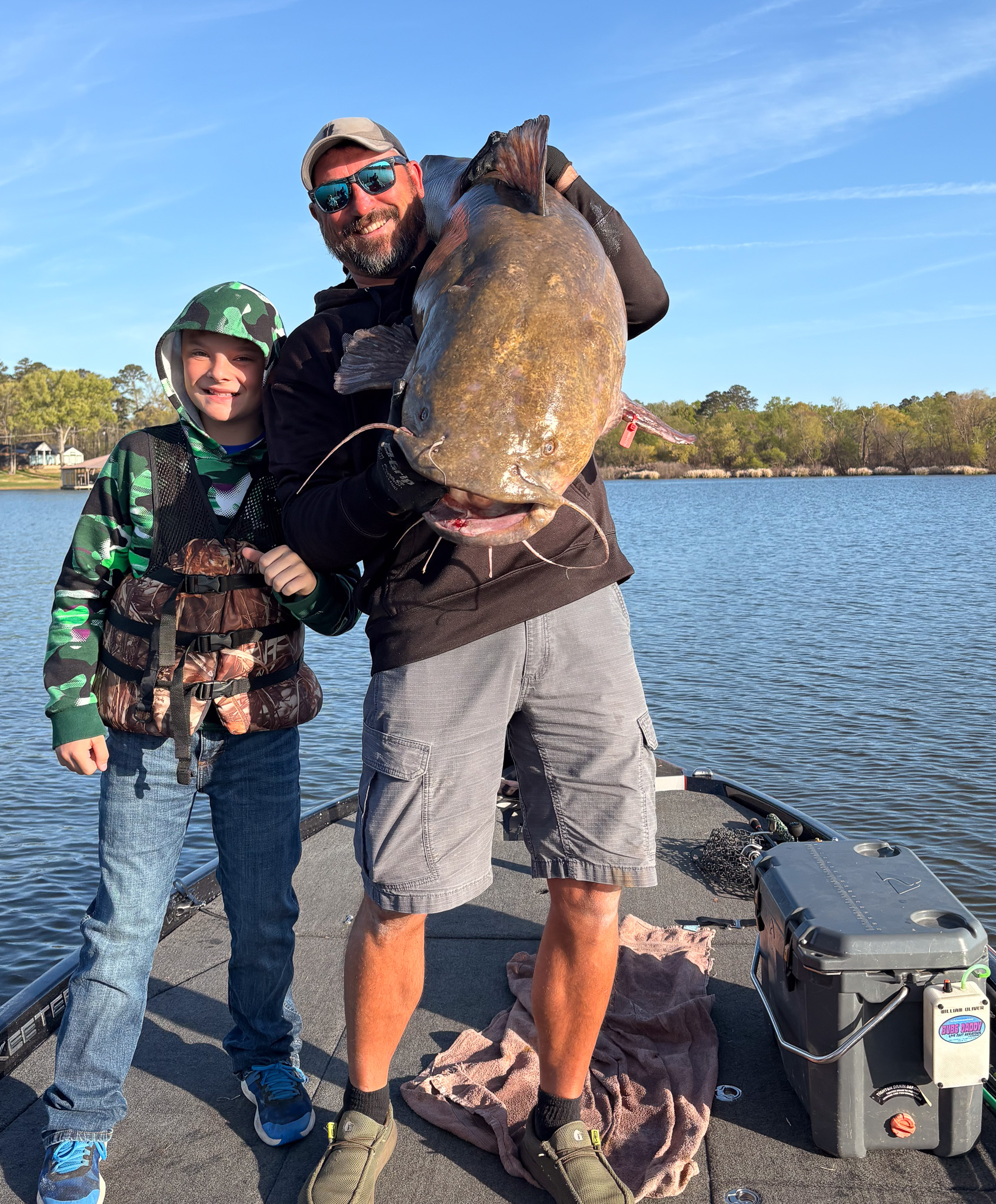 A man holds a giant flathead on his shoulder.