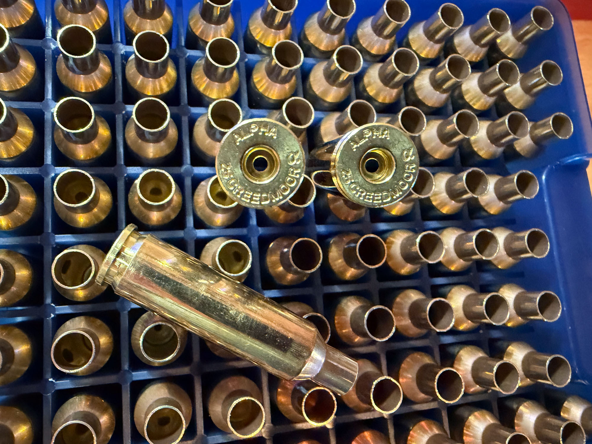empty brass cartridges in a blue handloaders box with twoo alpha 25 creedmoor headstamps