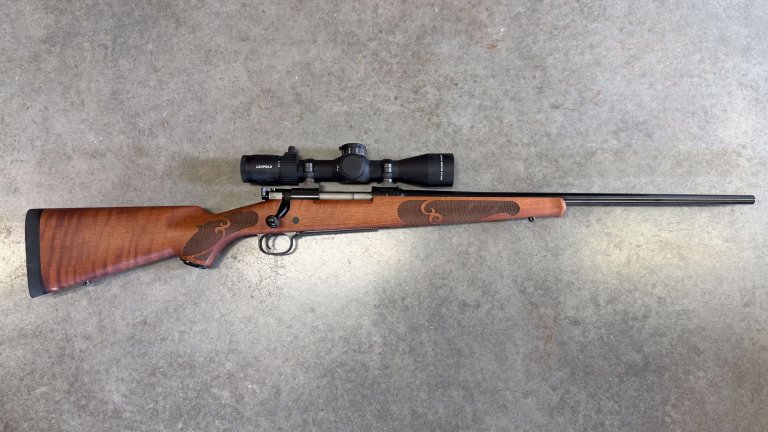 A wooden Winchester Model 70 rifle on concrete.