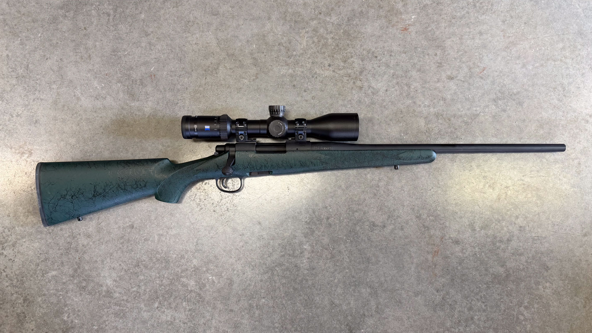 A green and black Sisk Remington 700 in .257 Roberts photographed on concrete.