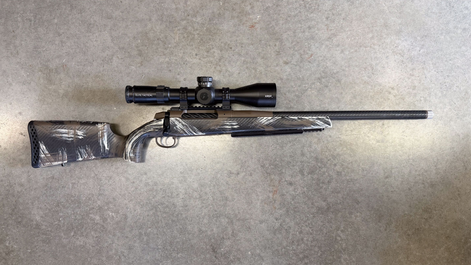 A black and white Weatherby 307 Alpine CT chambered in 25 Weatherby RPM on concrete.