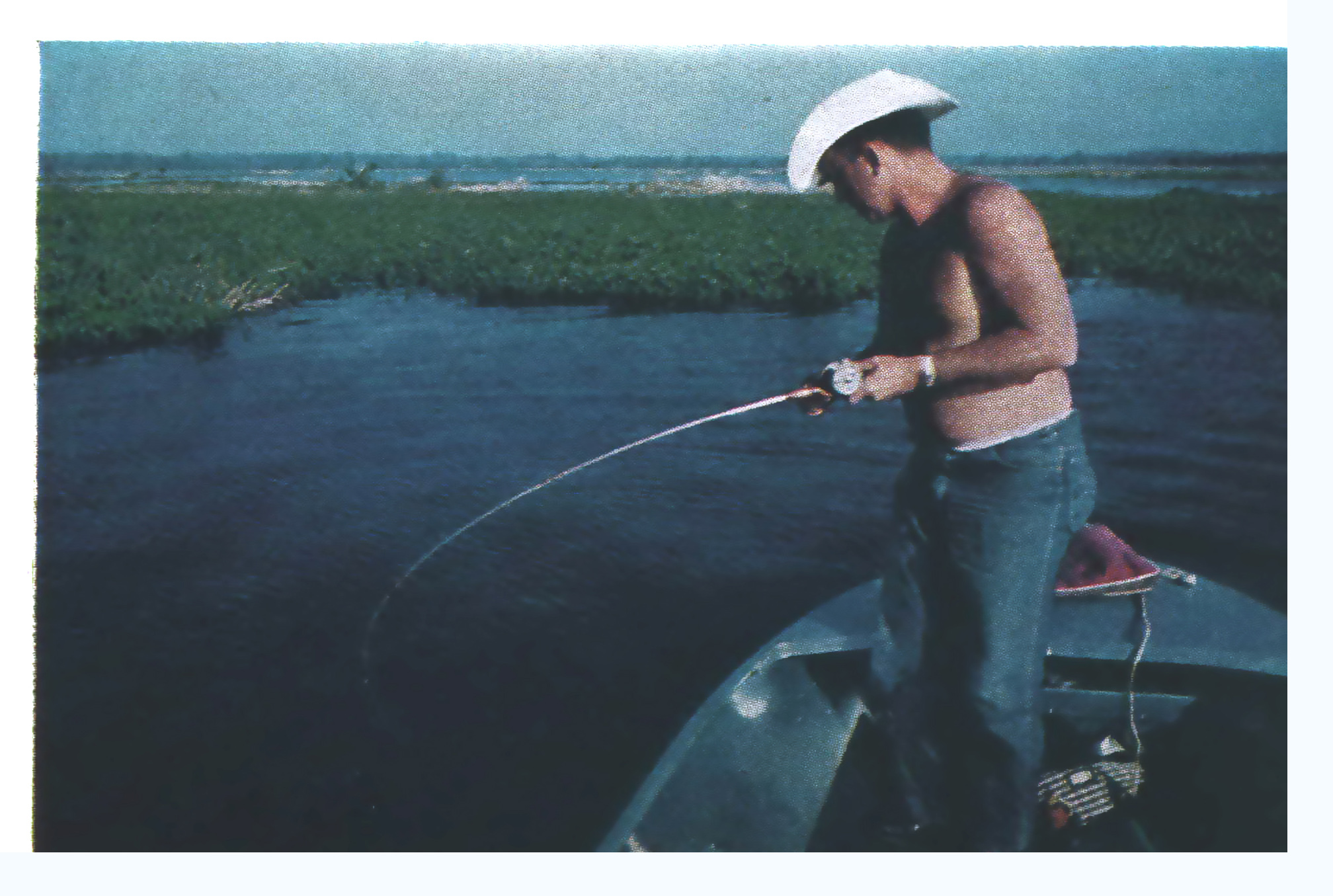 An old photo of a shirtless man in a cowboy hat bass fishing in Florida.