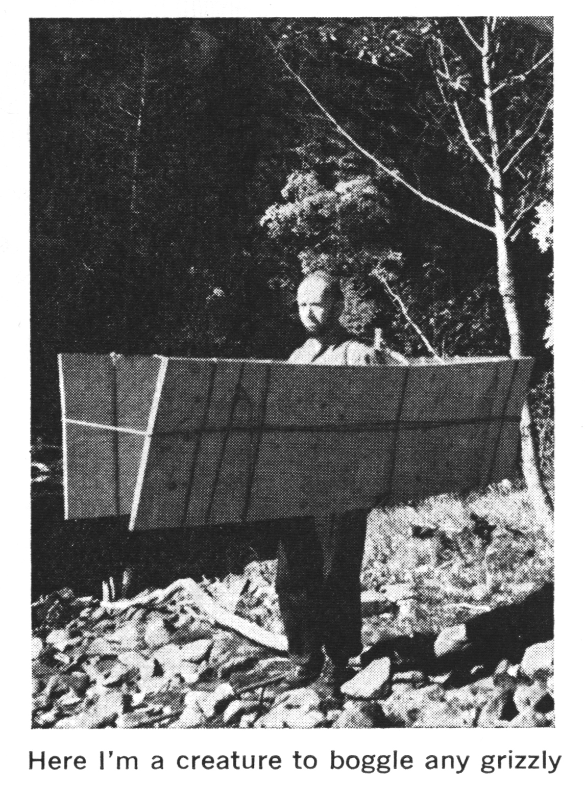 A black and white photo of a man in bear country with weird bear deterrent plywood around him.