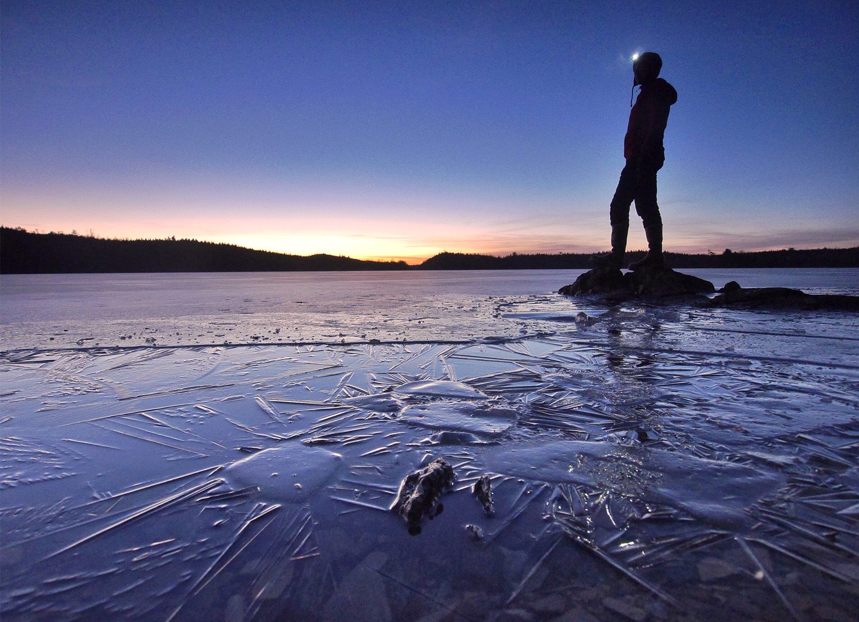 An explorer stands on frozen lakeshore in Boundary Waters Canoe Area Wilderness.