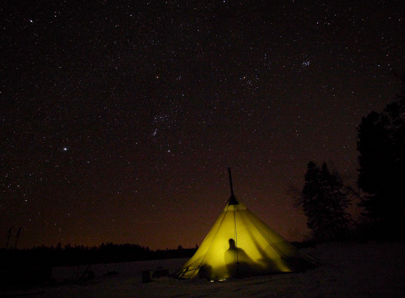 A lit up tent at night in the Boundary Waters.