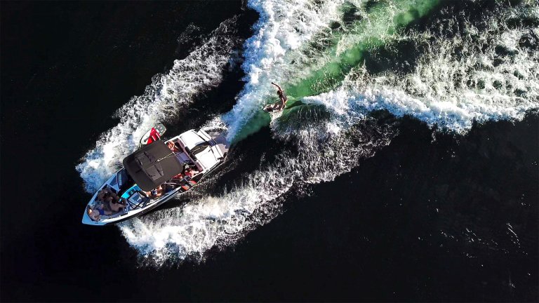 An aerial view of a wakeboat towing a wakesurfer.
