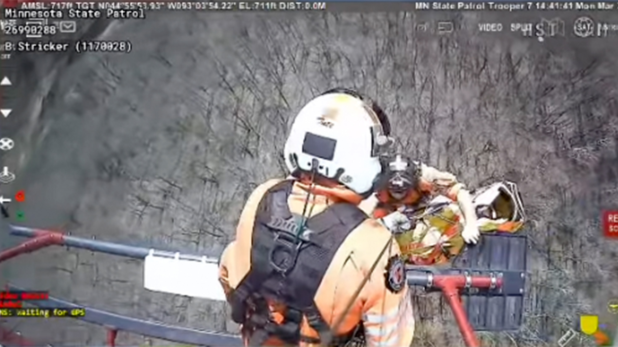 A rescue team hoists up a patient into a helicopter,