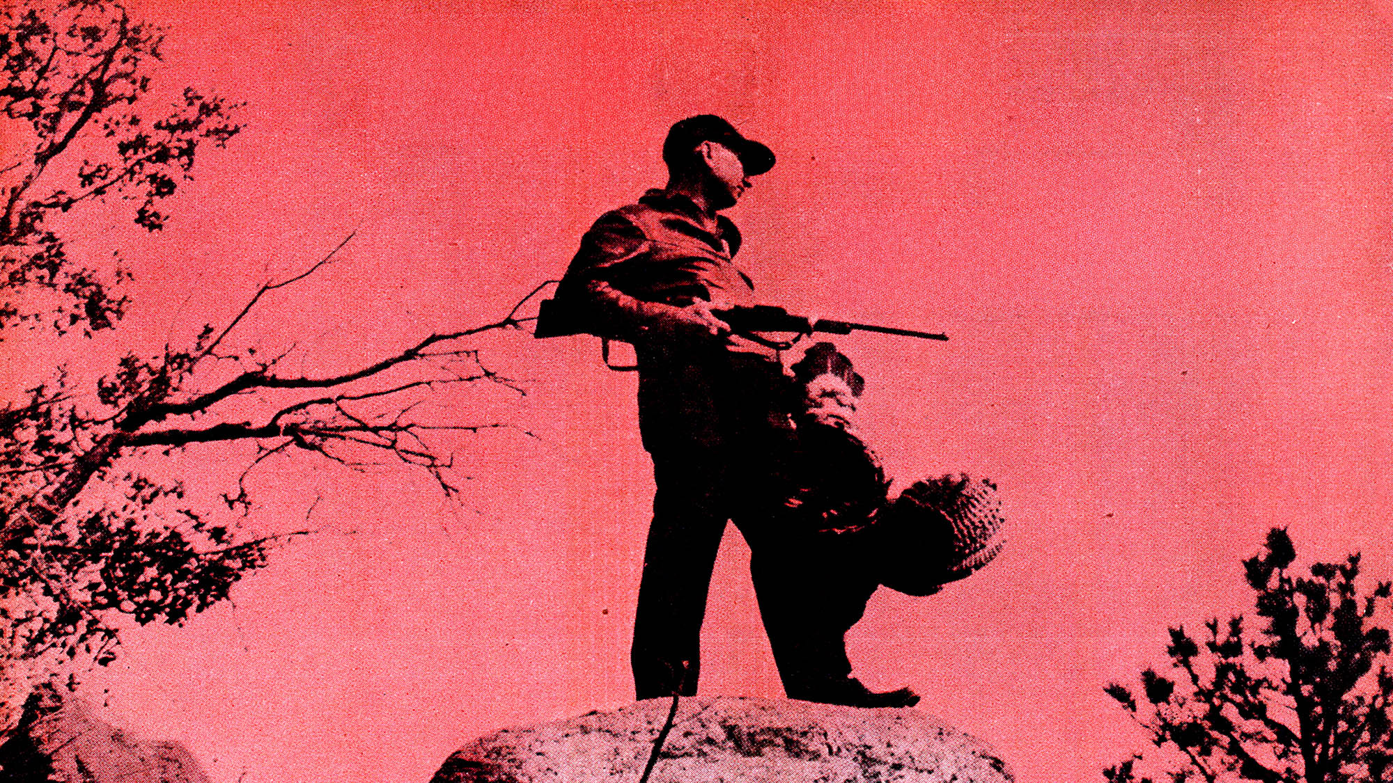 A man stands on a peak holding a turkey with a red background in a vintage photo.