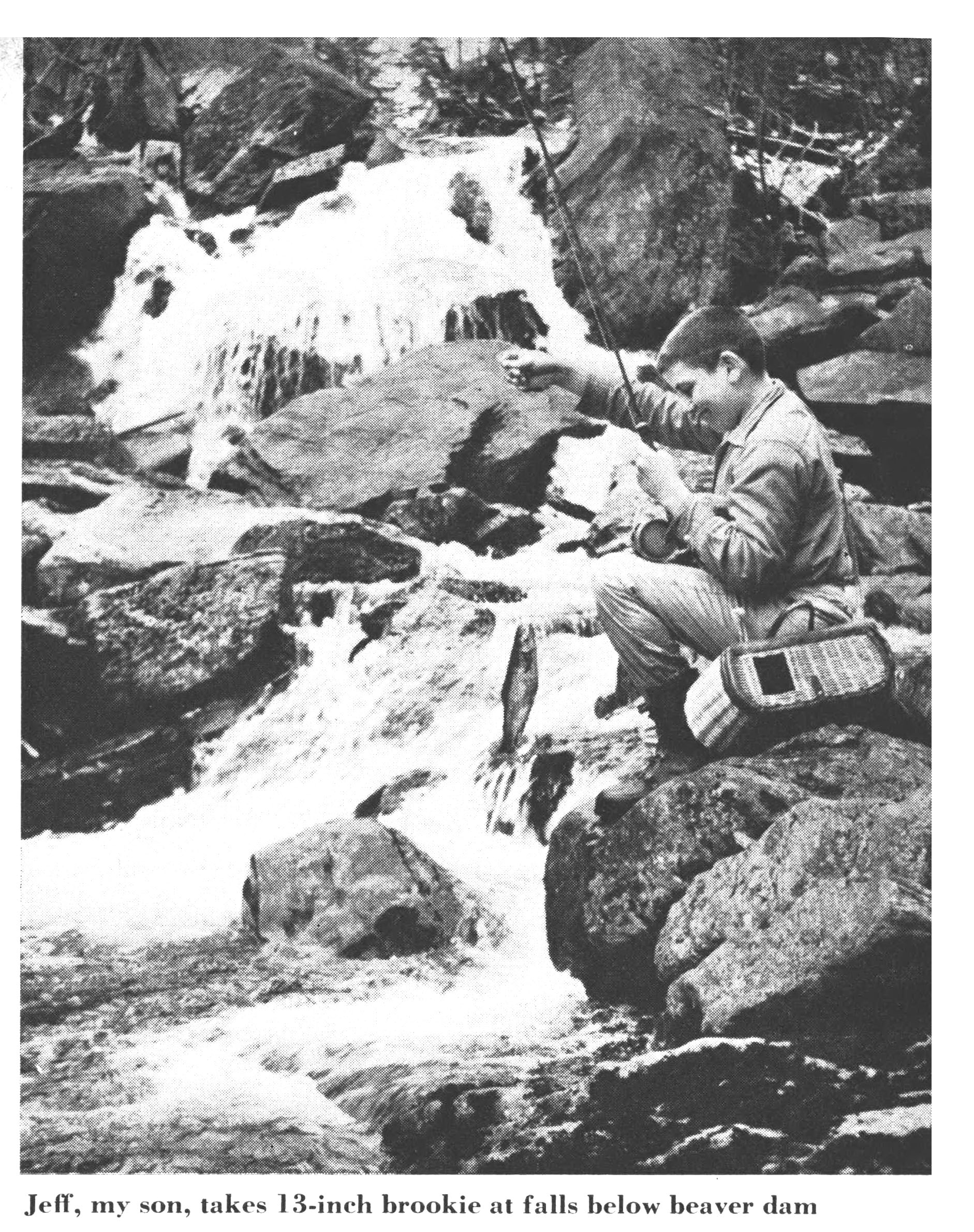 A black and white photo of a boy fishing from a beaver lodge.