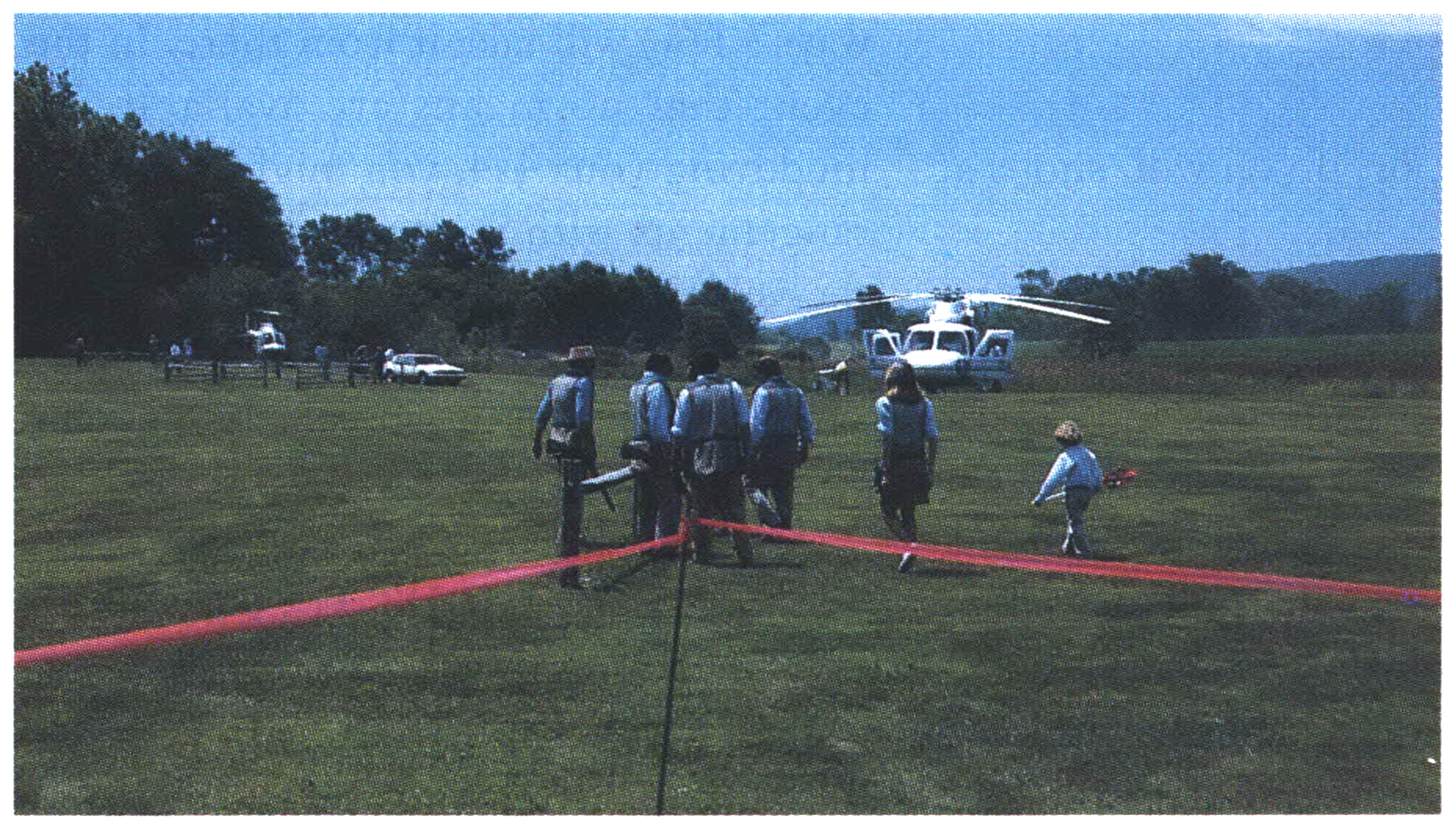 An old color photograph as people walk toward a helicopter.