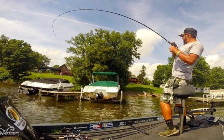 An angler sets the hook on a bass under a boat dock.