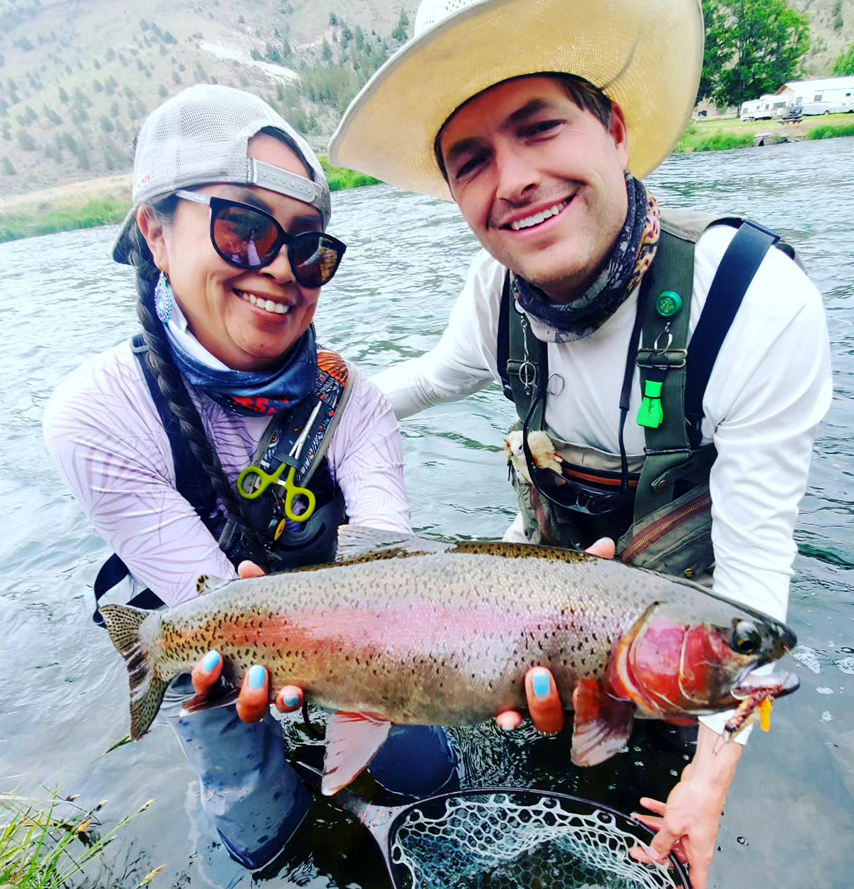 A fly fishing guide and her client with a healthy rainbow trout.