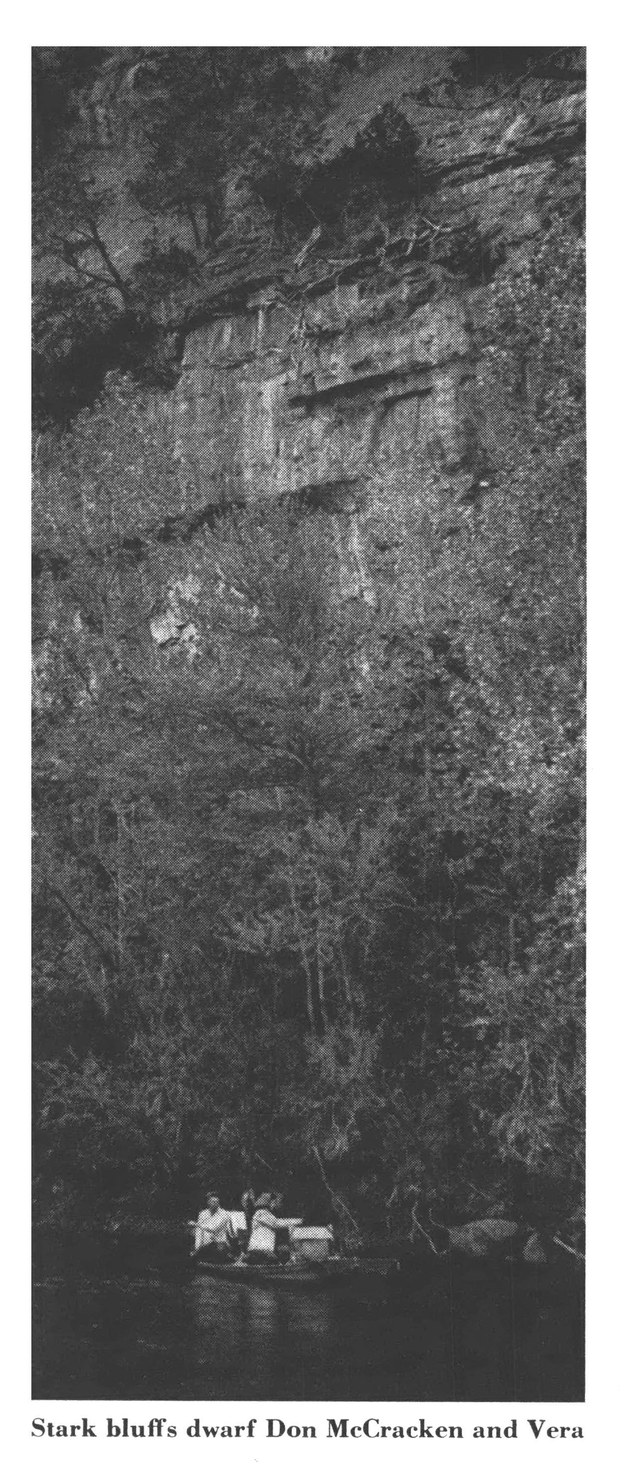 An old black and white photograph of a vertical sheer rock wall.