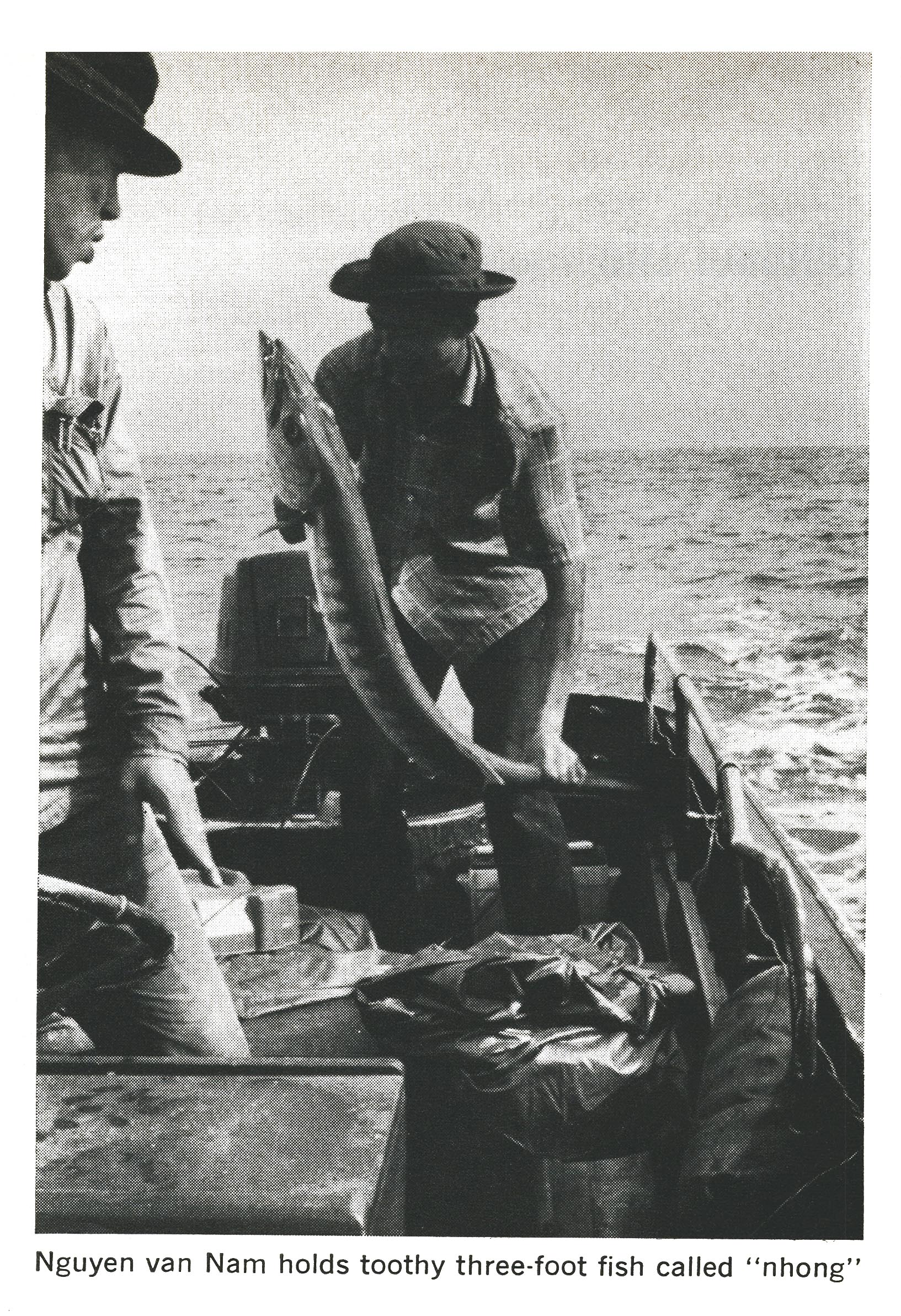 A man holds up a fish while fishing during the Vietnam war.