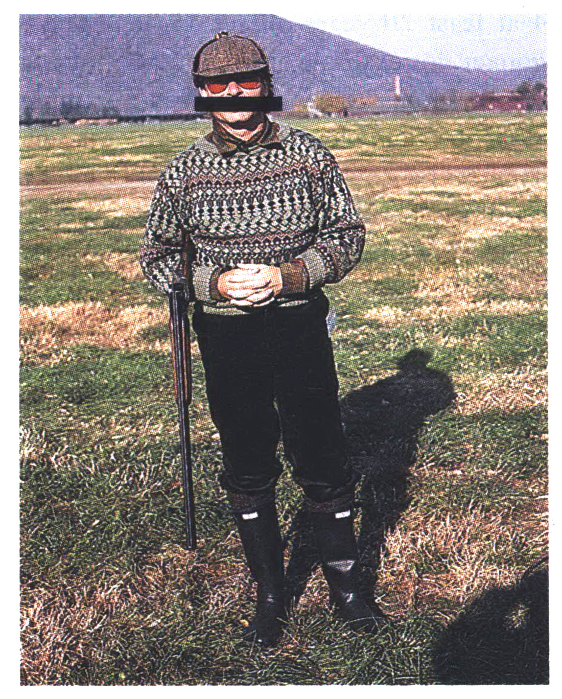 An old color photograph of a man with a shotgun in a striped sweater.
