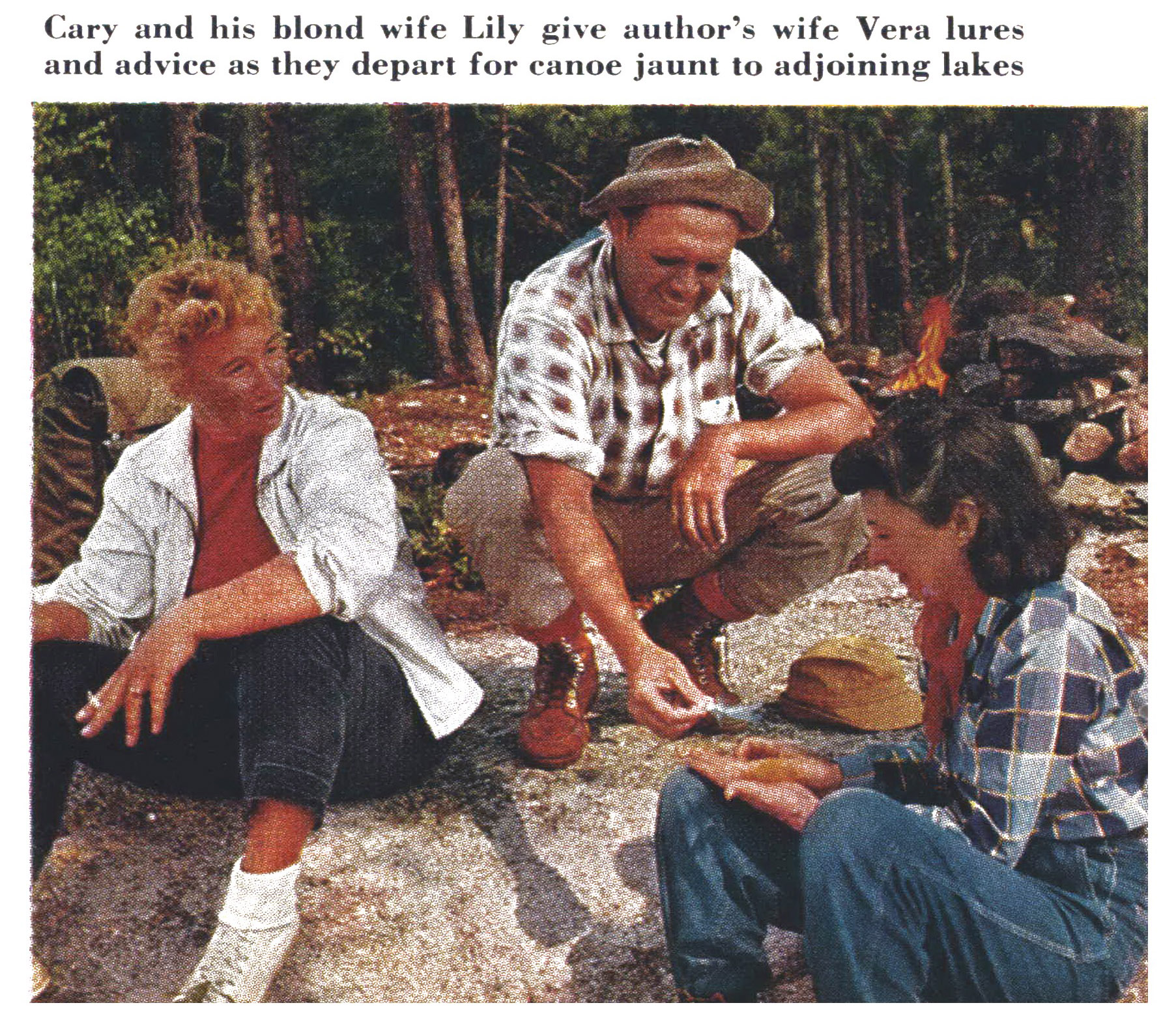 Three anglers sort lures and tackle beside a shore campfire before setting out by canoe.
