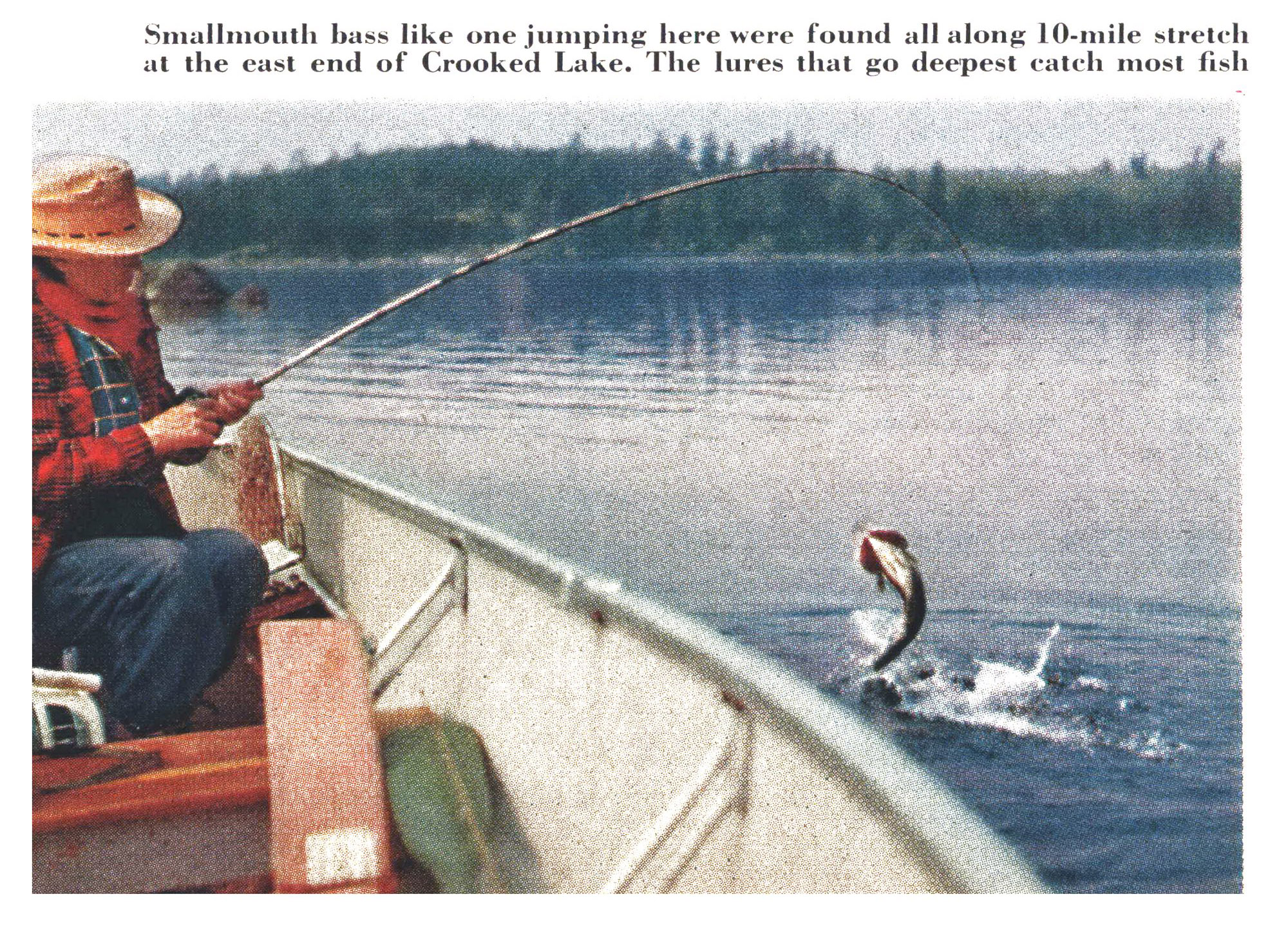A smallmouth bass leaps clear of the water beside a boat as an angler fights it in Crooked Lake.