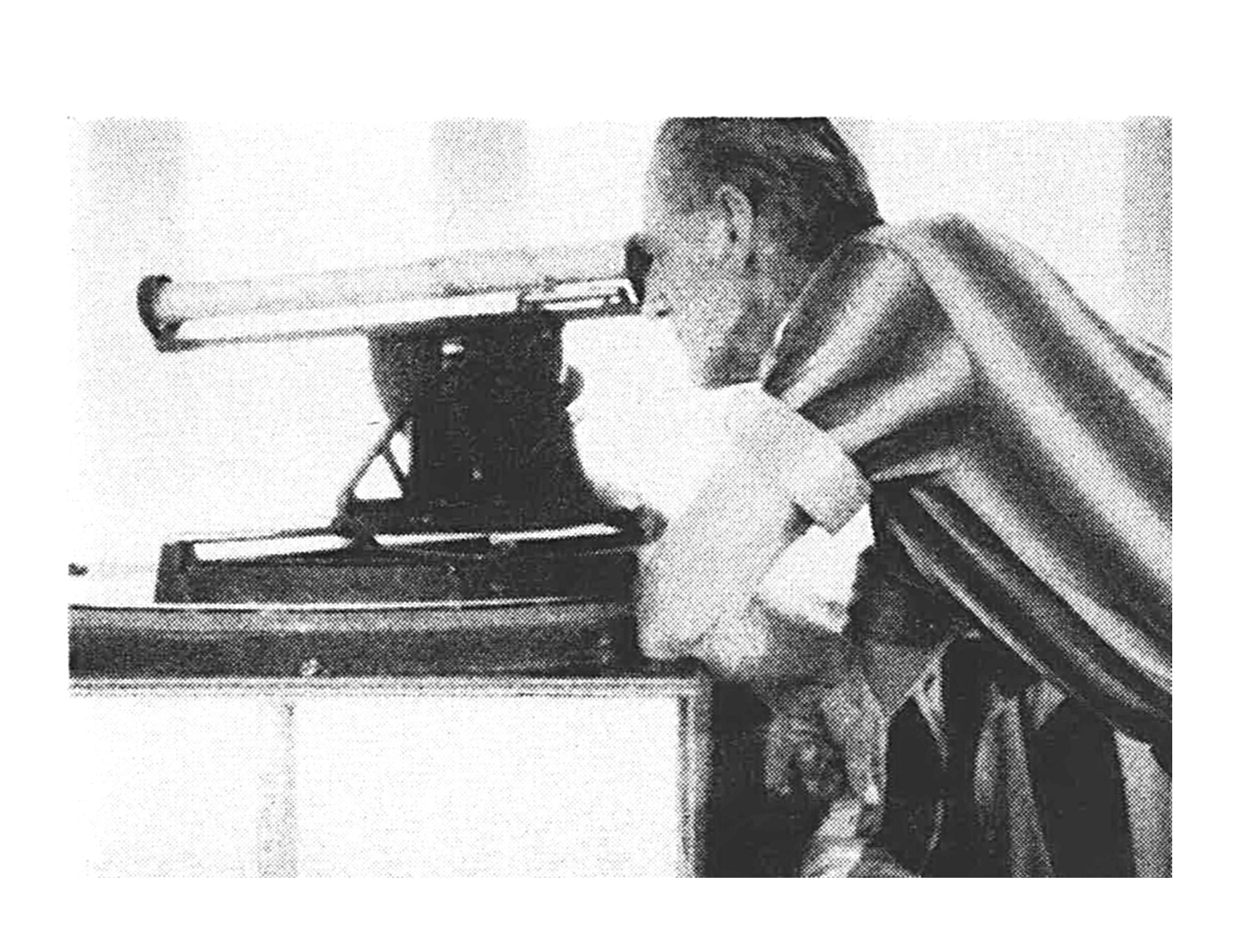 A black and white photo of a man looking through a finder.