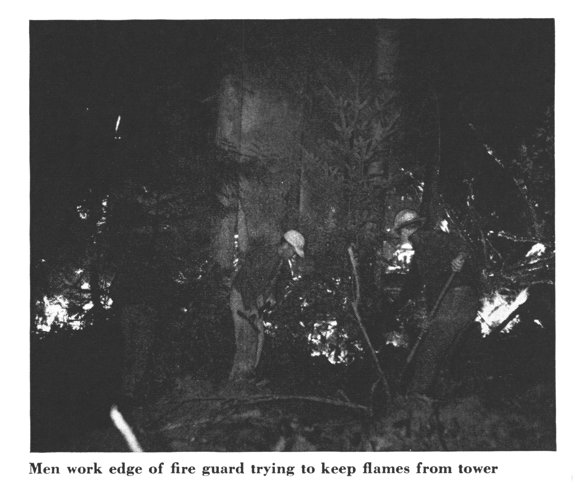 An old black and white fire of flames near a tower.
