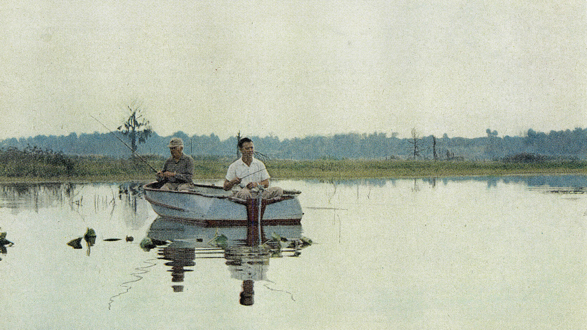 A vintage color film photo of a bass boat on a calm lake.