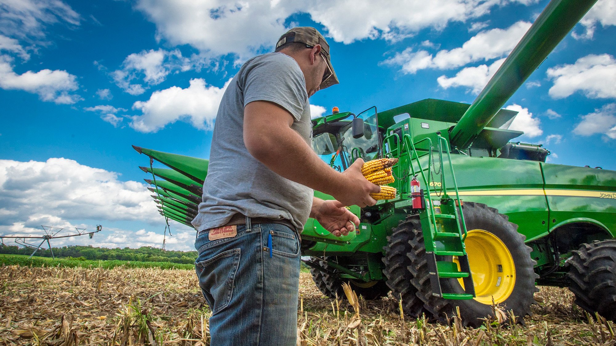 A farmer stands next to a tractor.
